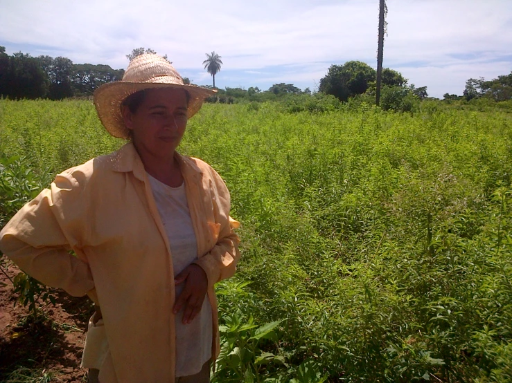 woman with hat on in field next to palm trees