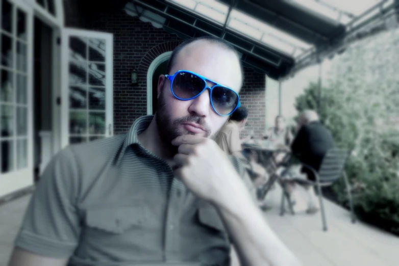 a man sitting outside wearing shades and a shirt