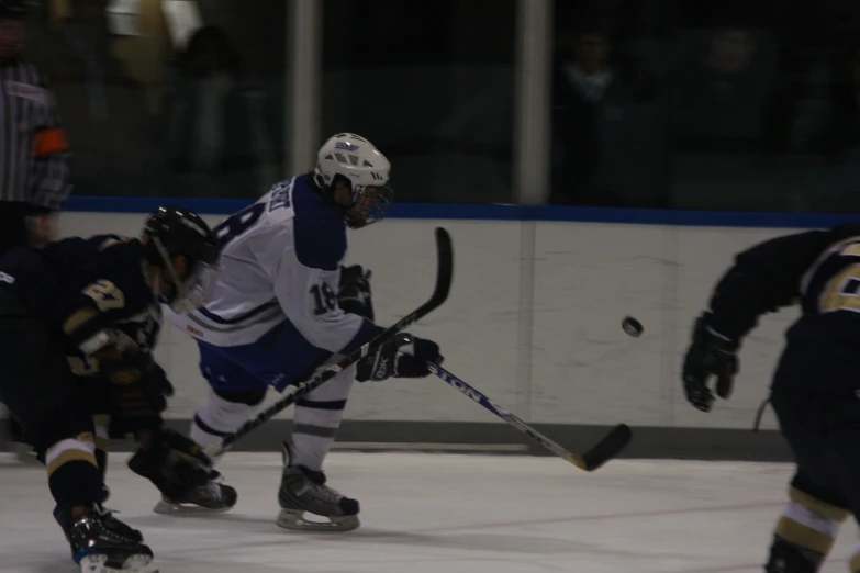 three people playing hockey and wearing protective gear