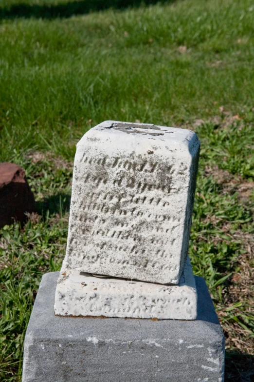 a monument with handwriting written on it stands in the grass