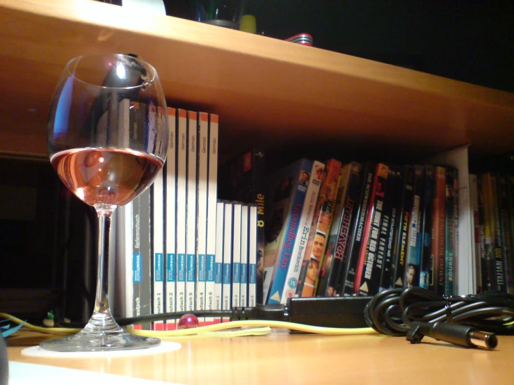 a wine glass and some books on the shelf