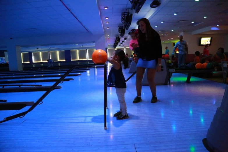 two girls are on a bowling alley while others watch