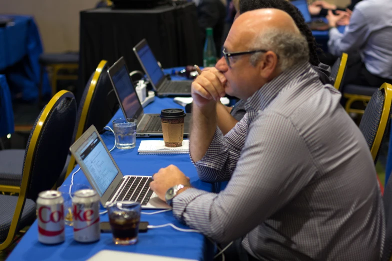 an older man sitting at a table using a laptop computer