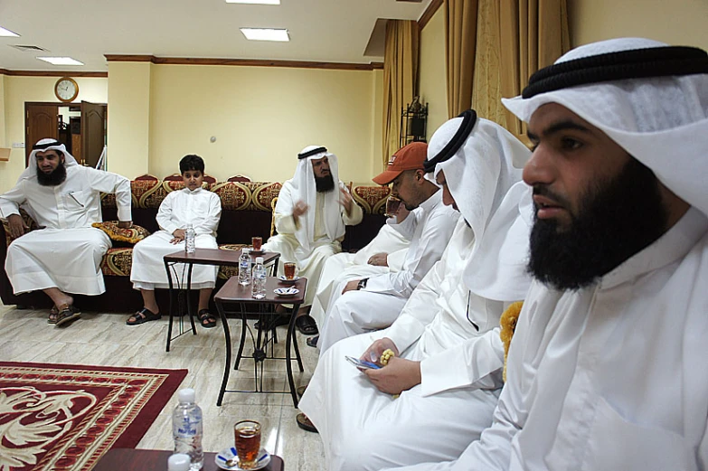 a group of men sit in chairs with coffee cups on their feet