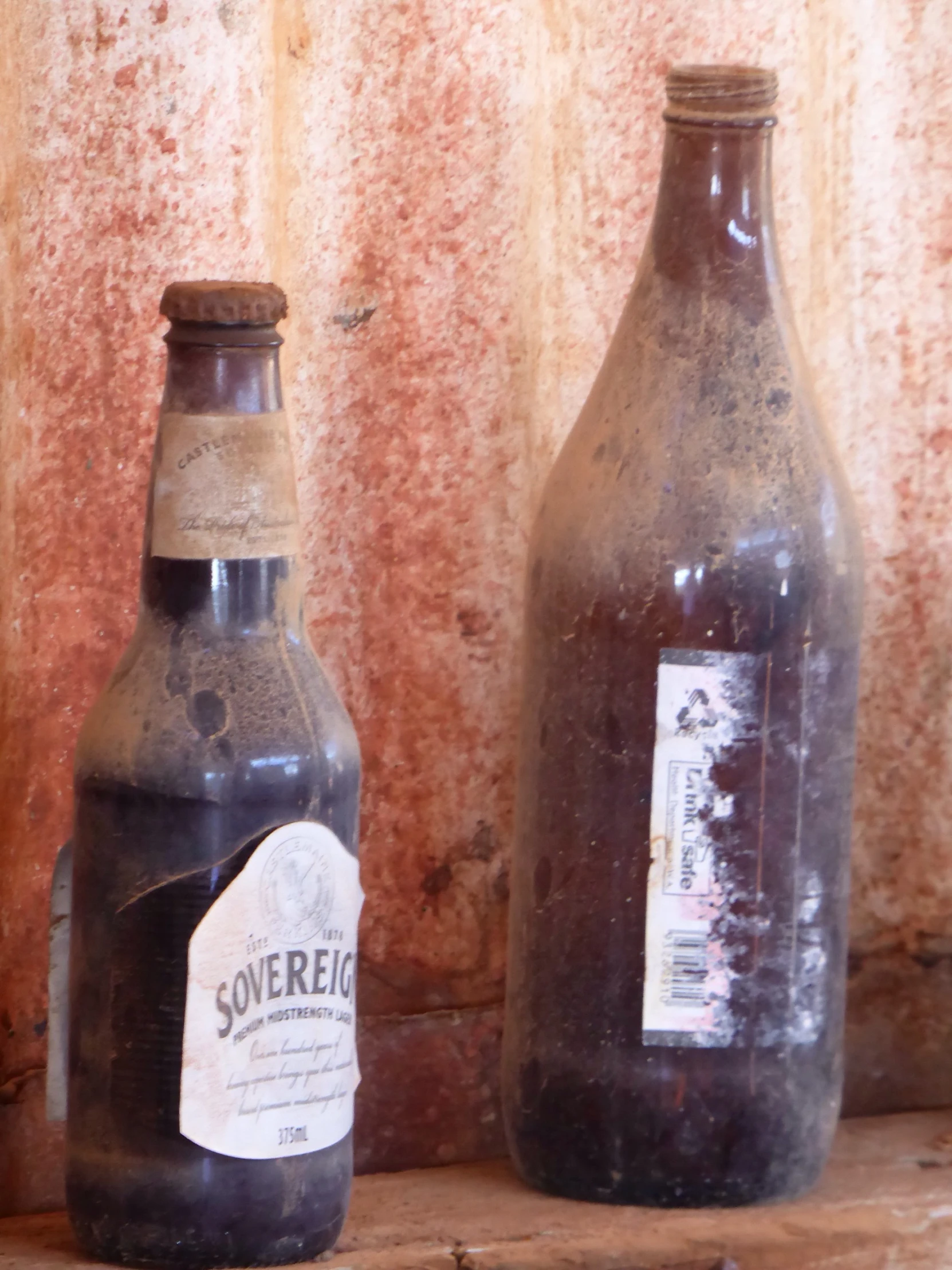 two brown bottles on a counter next to a wall