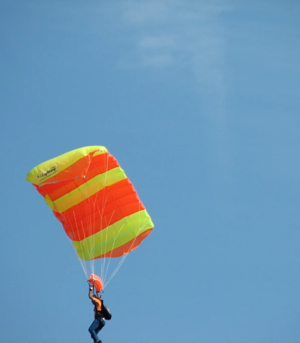 a man flying a large orange and yellow kite