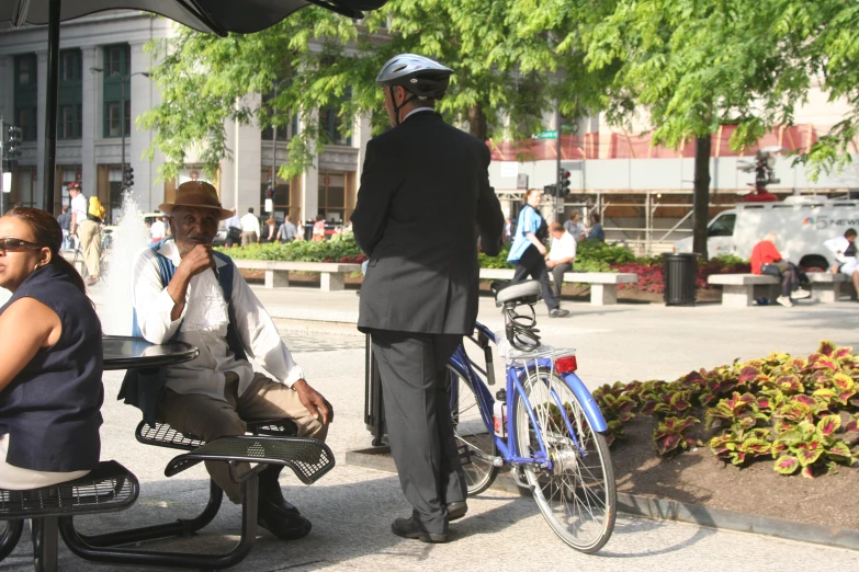 a man in a suit sits on a bench near a woman wearing sunglasses