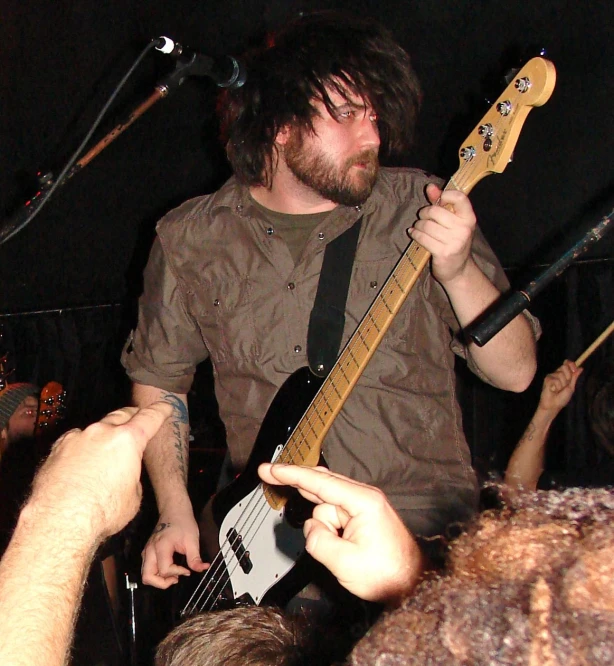 a man playing a guitar with some fans watching