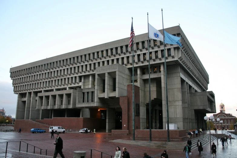 a tall gray building with two flags on top of it