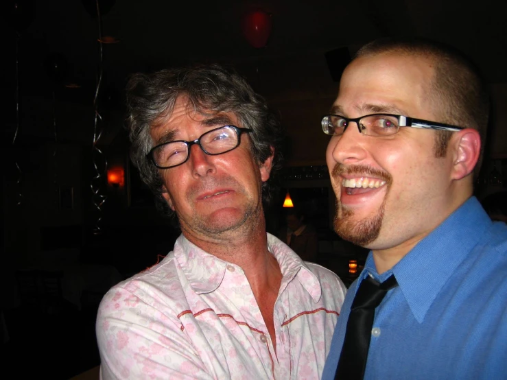 two men in glasses and a tie with one looking forward