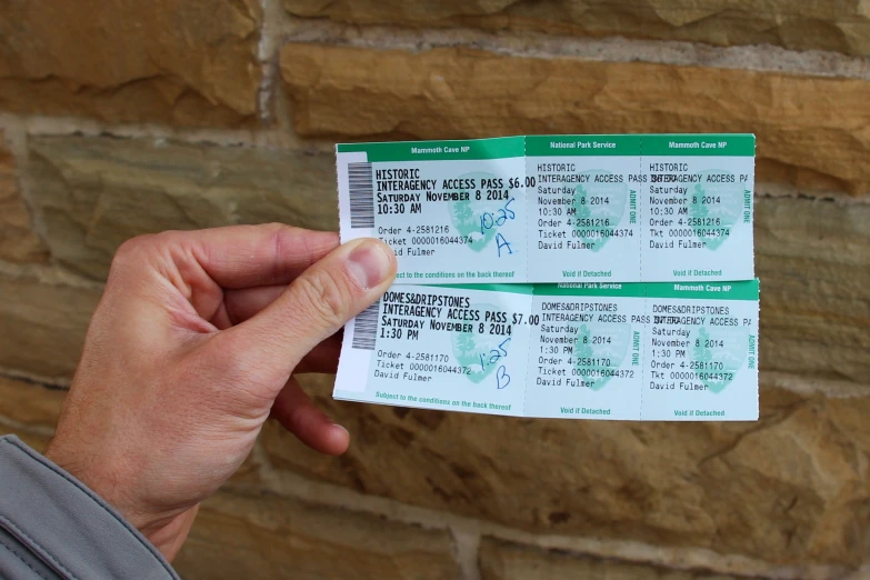 the tickets to the concert are held in front of a brick wall