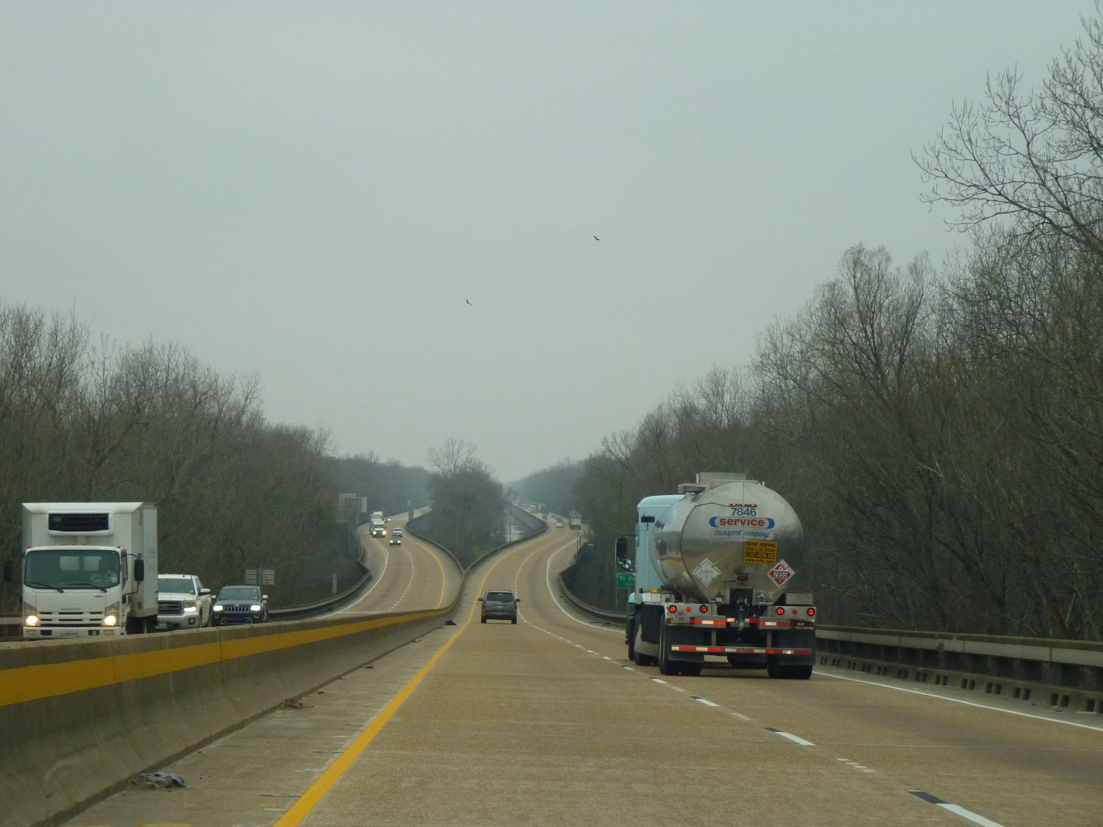 vehicles on a highway with a large cement mixer on the road