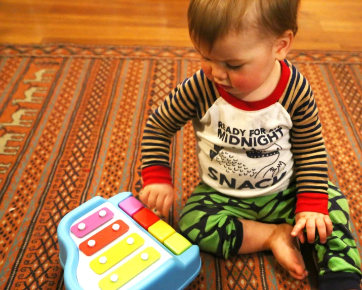 small toddler plays with toy blocks while sitting on rug