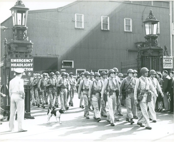 an old pograph of a group of men in uniforms walking down a street
