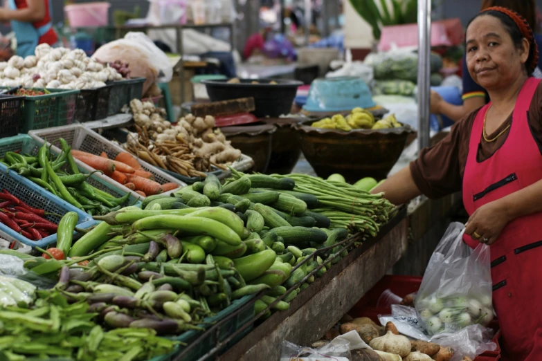 the woman is selling vegetables and greens on display