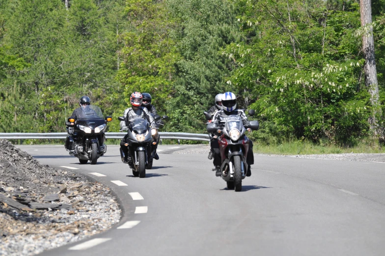 three men are riding motorcycles on the road