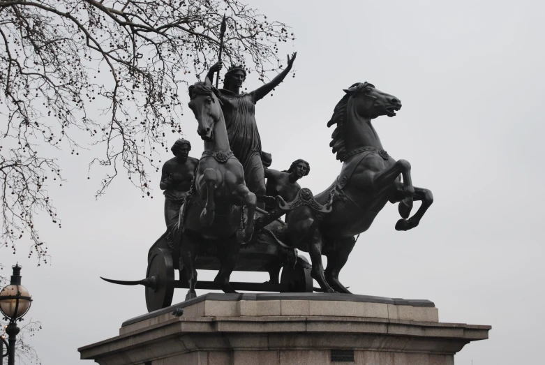 an ancient statue with people riding horses next to it