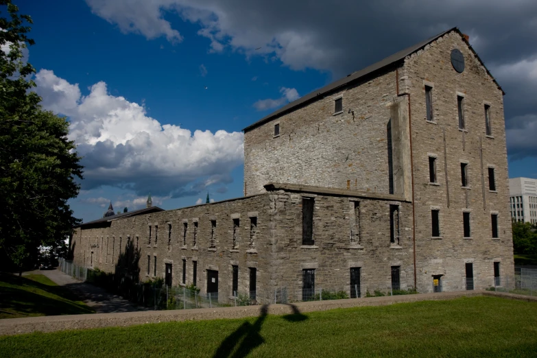 a brick building sits beside a lake under some clouds