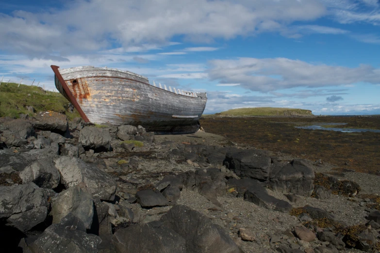 a small boat lying on the ground among rocks