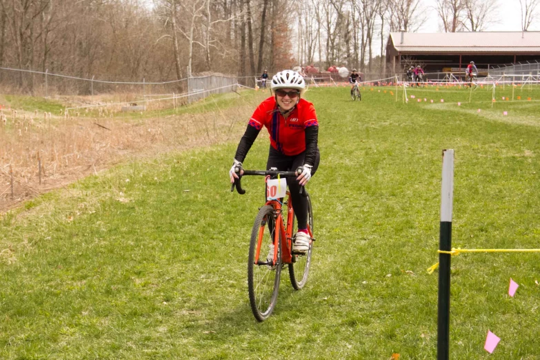 a woman rides her bike through a grassy area