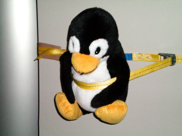 a stuffed animal penguin has a tape measure on it's belt