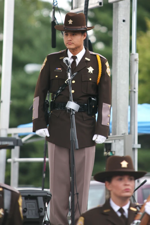 an officer with military uniform and microphone in front of another