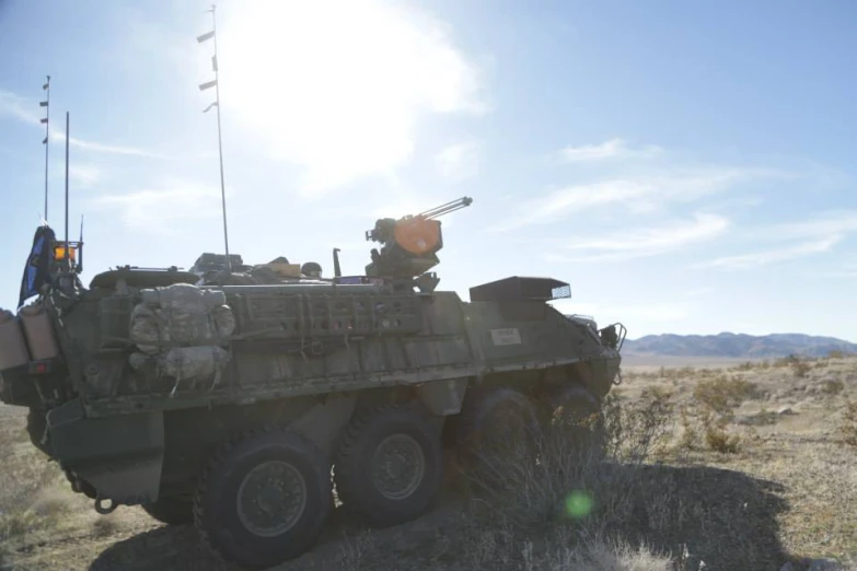 an army vehicle sitting in the desert near a flag pole