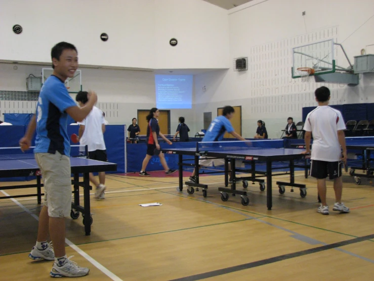 a group of young men standing in front of ping pong tables