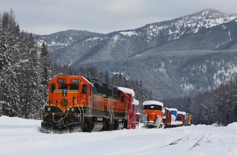 train passing by mountain with snow covering it