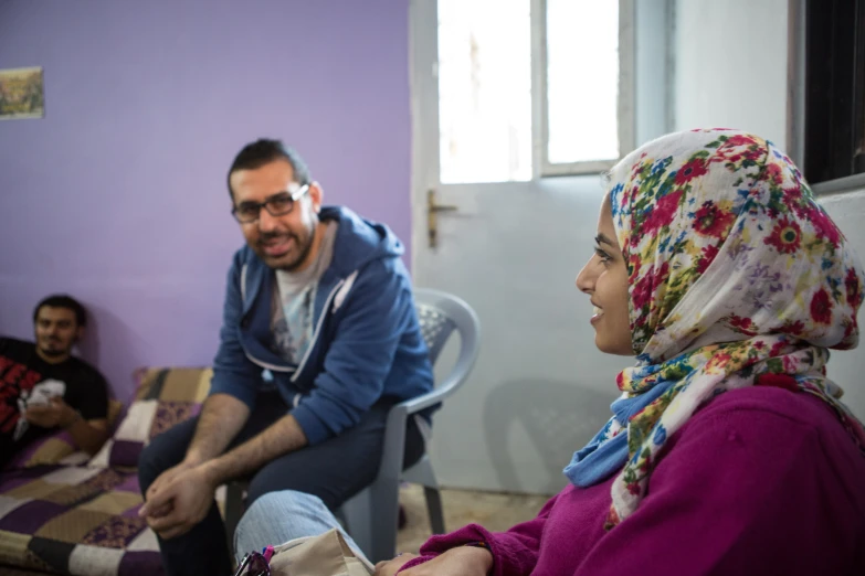 the woman sitting on a chair has a purple scarf and her friends in chairs