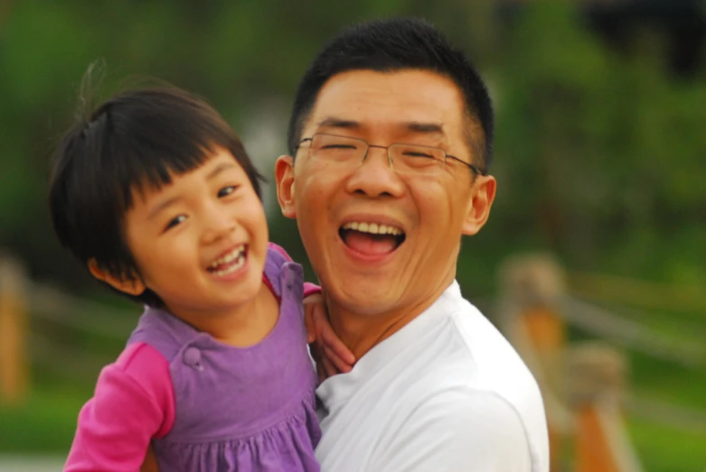 the man is holding a little girl and she is smiling at her