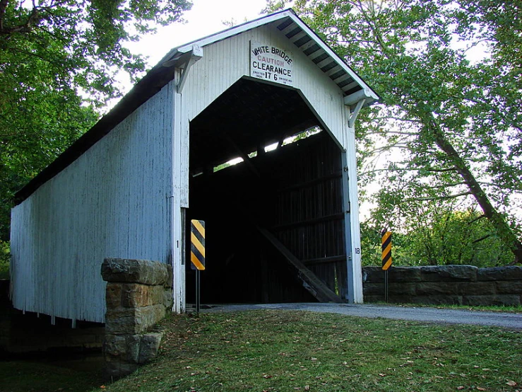 a big white covered bridge with a yellow guardrail on the side