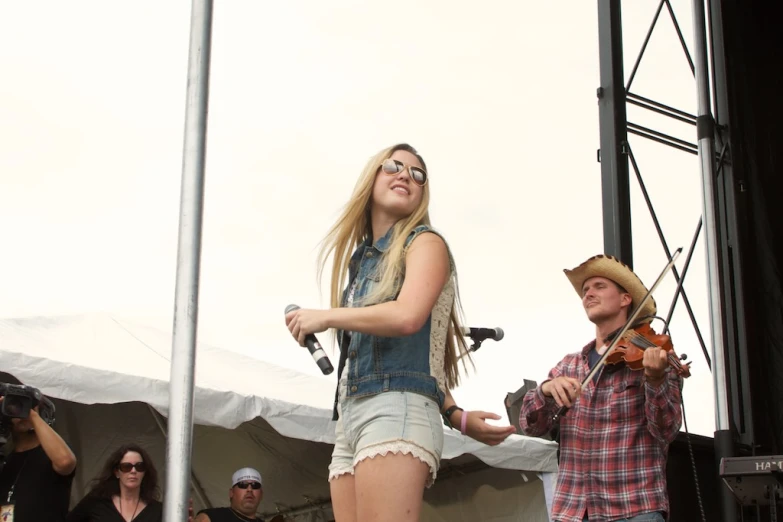 a woman playing a violin while singing on stage