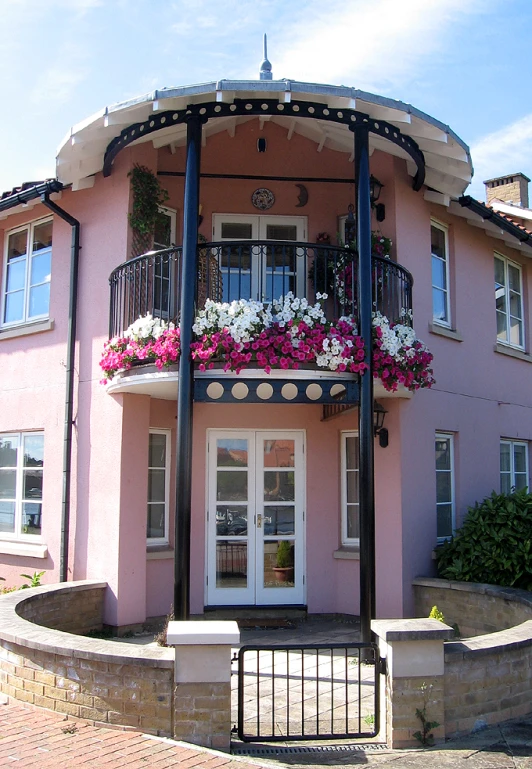 a pink building with white doors and window boxes