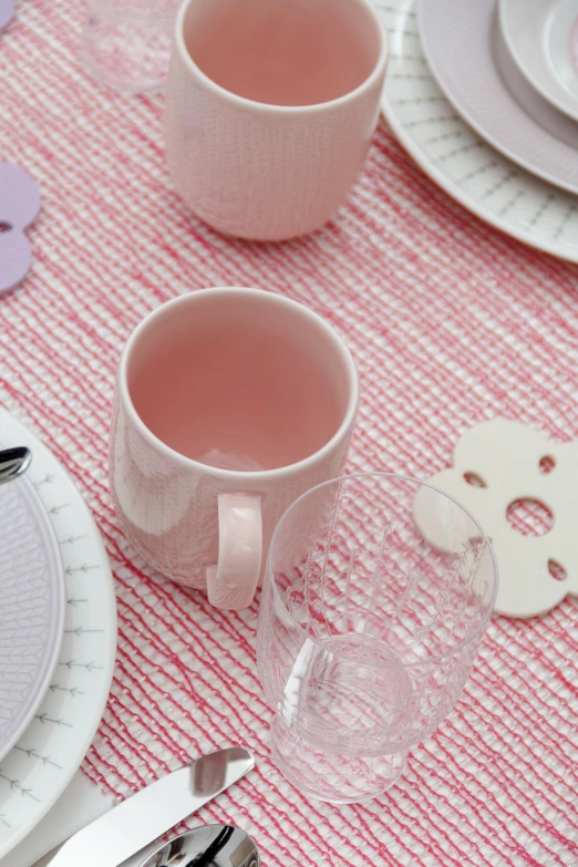 a close up of two cups on a table near other place settings