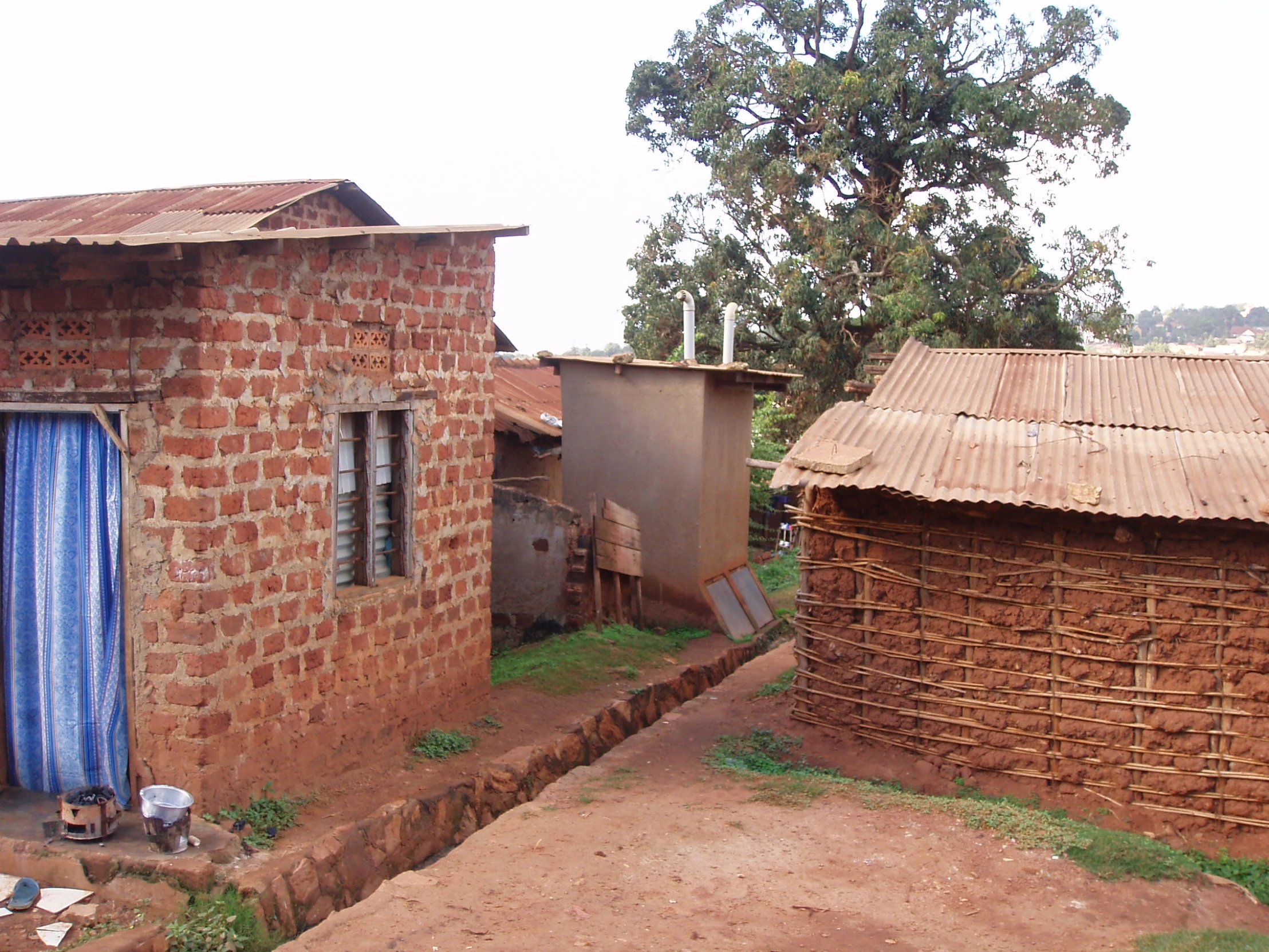 a dirt field that has a brick house in the background