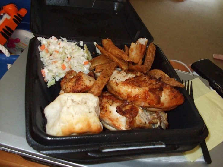 a food tray with chicken, rice, fries and coleslaw