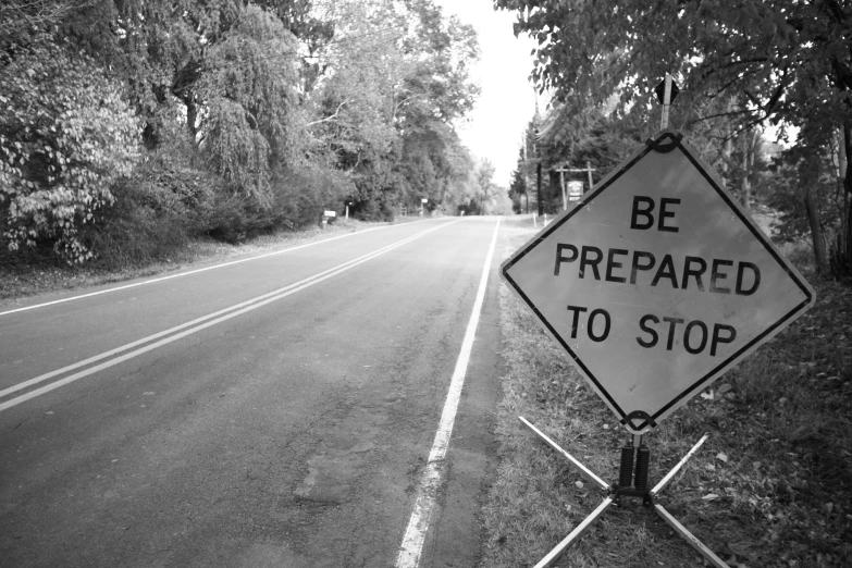 a black and white picture of a warning sign on the side of a road