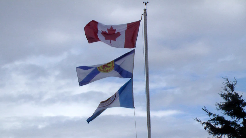 three canadian and british flags blowing in the wind