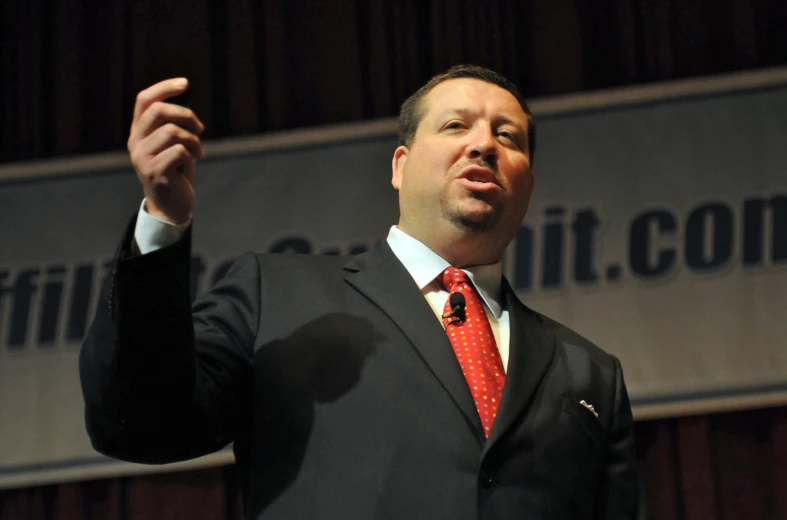 a man in a suit and red tie speaking