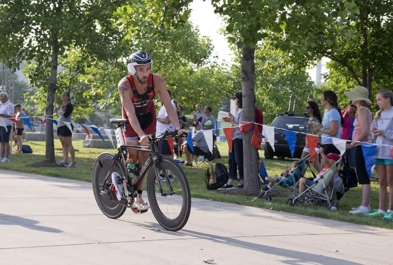 a man riding a bicycle down a street while people watch