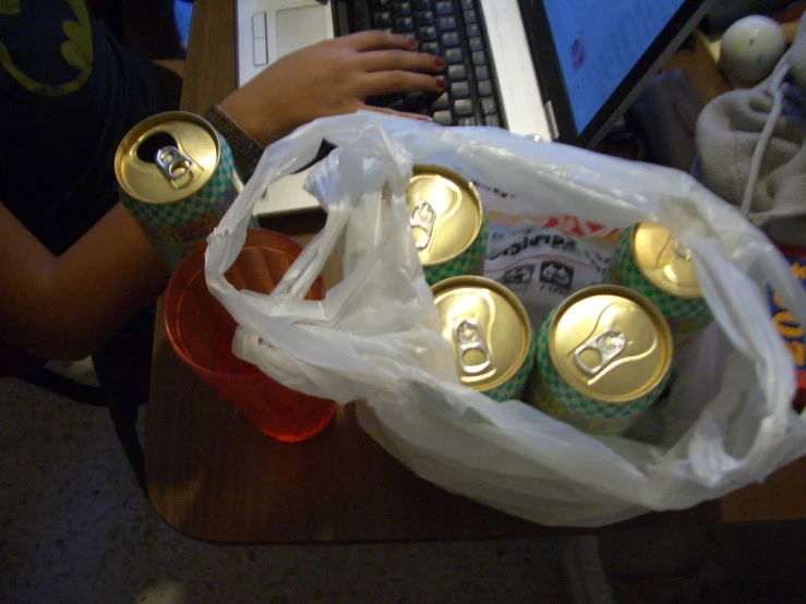 a person using a laptop with a bunch of beer cans in front of them