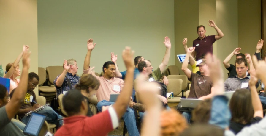 a large group of people are raising their hands