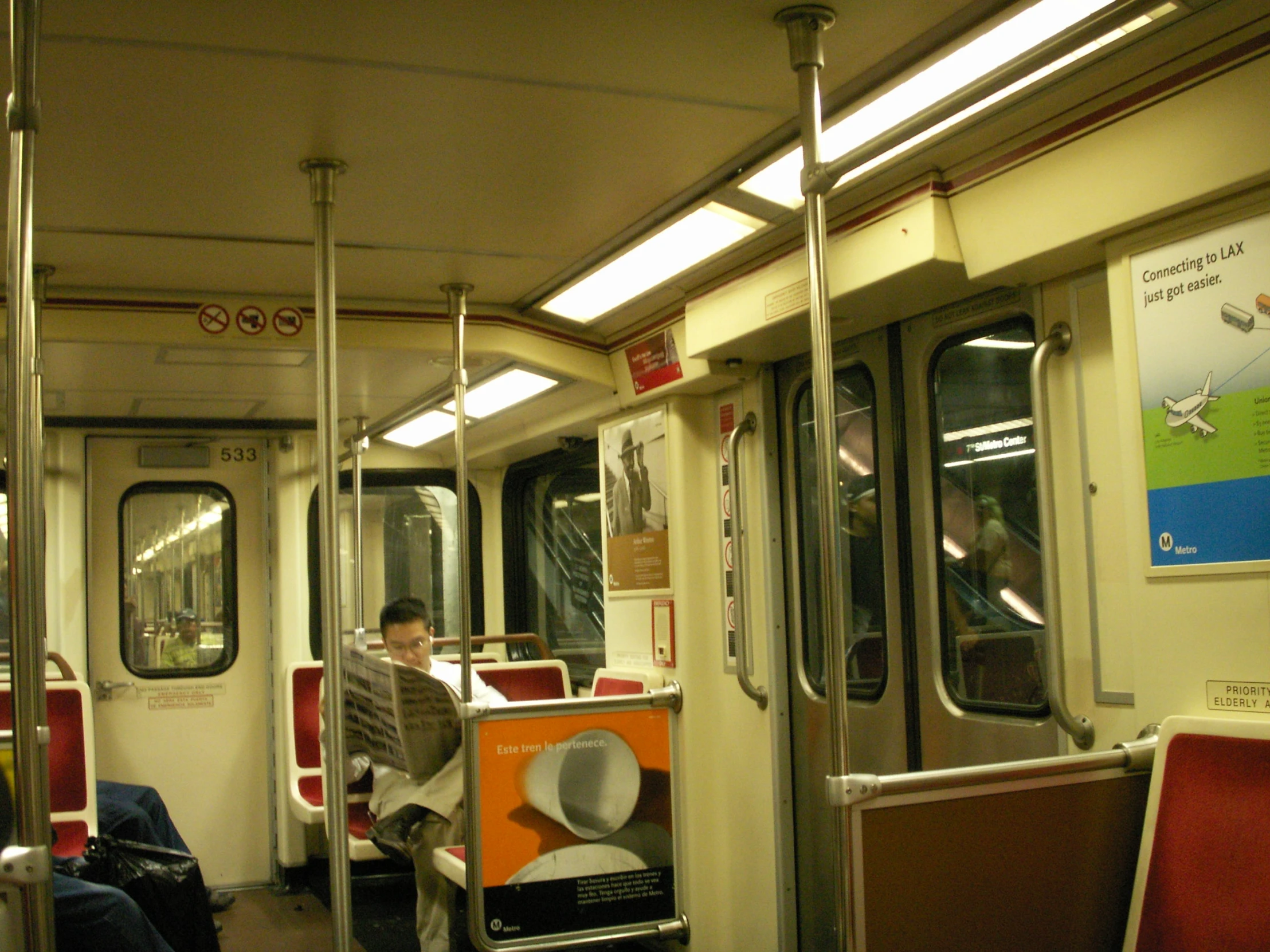 a man sits inside a commuter train looking at his laptop