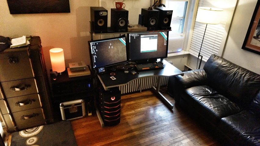 a desk with a couch, speakers, tv and a dvd player