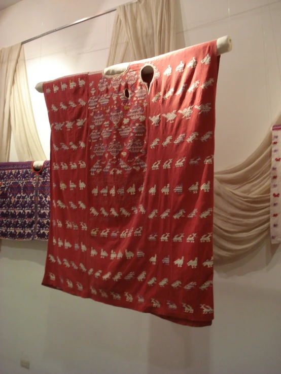 two red bedspreads hanging from metal racks