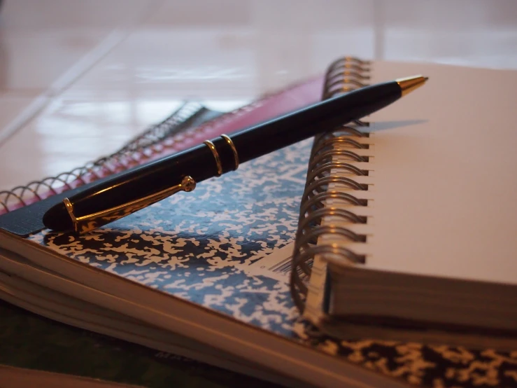 a spiral notebook and pen sitting on top of each other
