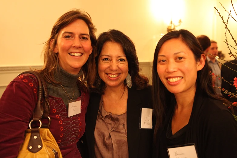 three women smile at the camera while posing