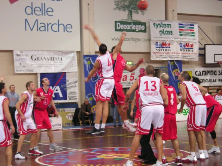 many basketball players in red and white uniforms on a court