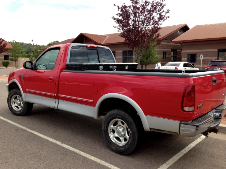 a red truck is parked in a parking space next to some buildings